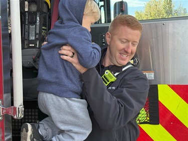 Firefighter helping a young boy get down from a fire truck