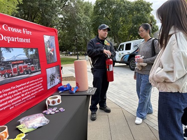 During Eagle Fest at UWL, a firefighter shows a student how to use a fire extinguisher.