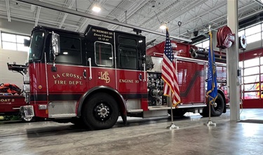 Red fire engine in fire station bay with American and Wisconsin state flags
