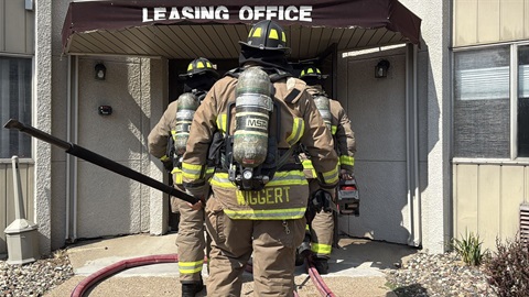 Firefighters walk into the entrance of the apartment building to do overhaul.