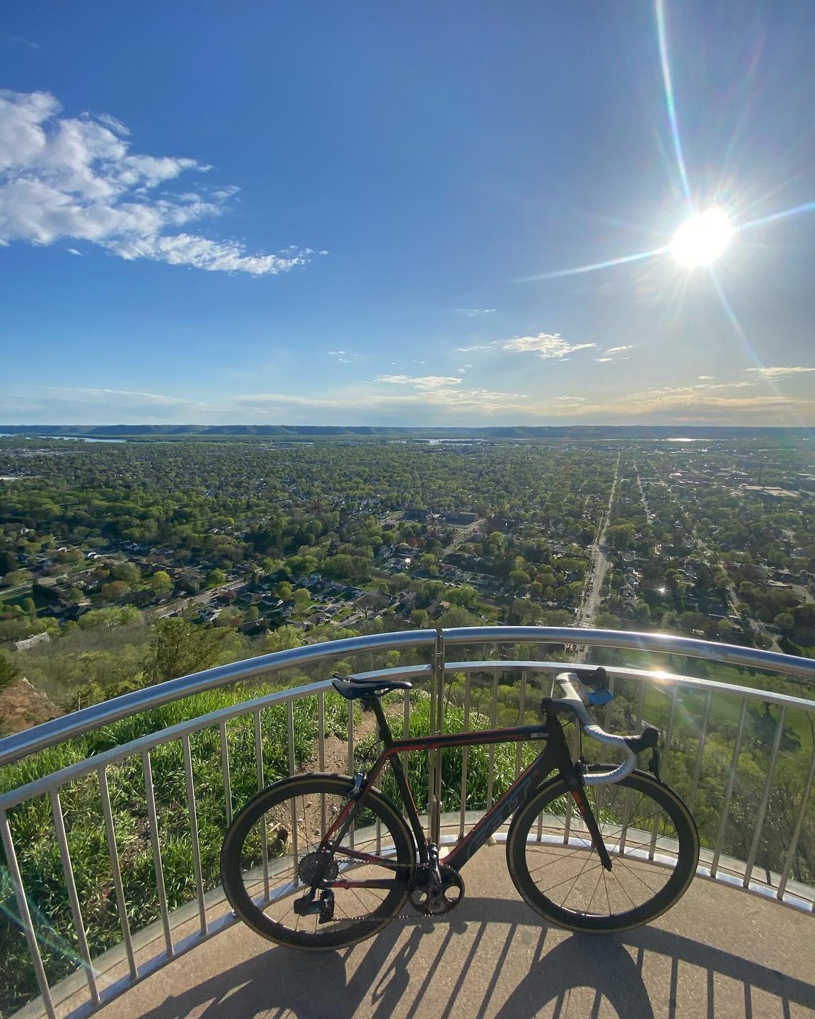 Bike leaning against a railing at the Grandad Bluff overlook with view over the bluff.