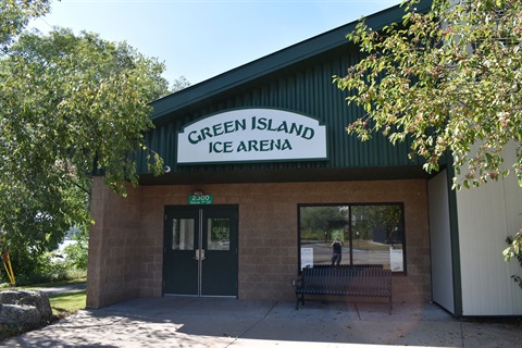 The Green Island Ice Arena building with a sign above the entrance and trees on either side.