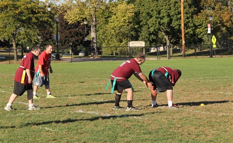 group of 4 special olympics athletes playing flag football. playing offense and about to hike the ball. 