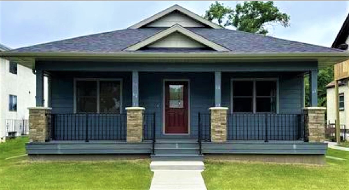 A blue house with a covered porch supported by stone-clad columns and a dark red front door.