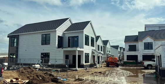 In-progress construction of a white two story town home on a muddy spring day at Riverpoint District 
