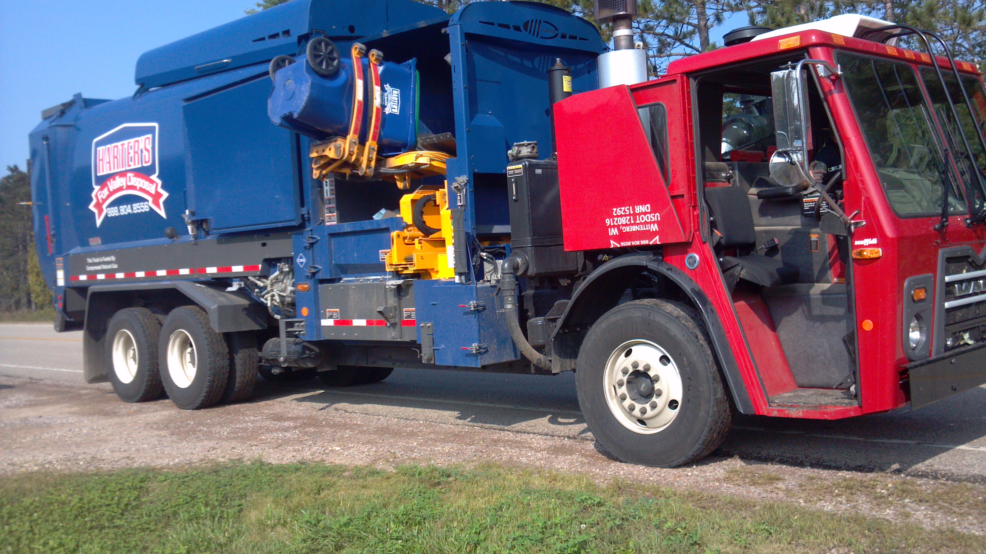 City-service contractor Harter's Quick Clean-Up garbage truck lifting a cart into the hopper