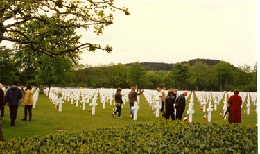People walking in the grass among white cross grave markers for American military soldiers