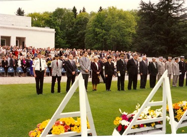 Crowd of people standing in front of memorial flowers for American soldiers