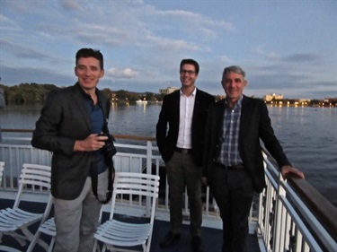 Three men standing on the deck of a boat over open water.