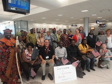Group of people gathered in an airport terminal to meet passengers with signs and American flags