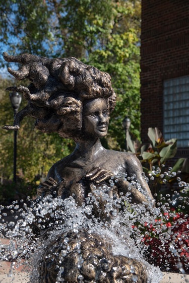 Bronze fountain statue of a woman with water spraying