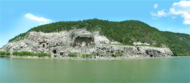 View of caves with Buddhist statue carvings in the side of the cliff as seen from across the water
