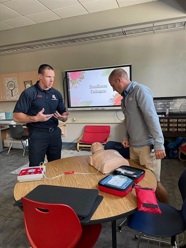 LCFD Firefighter explaining how to use an A.E.D to a local school teacher