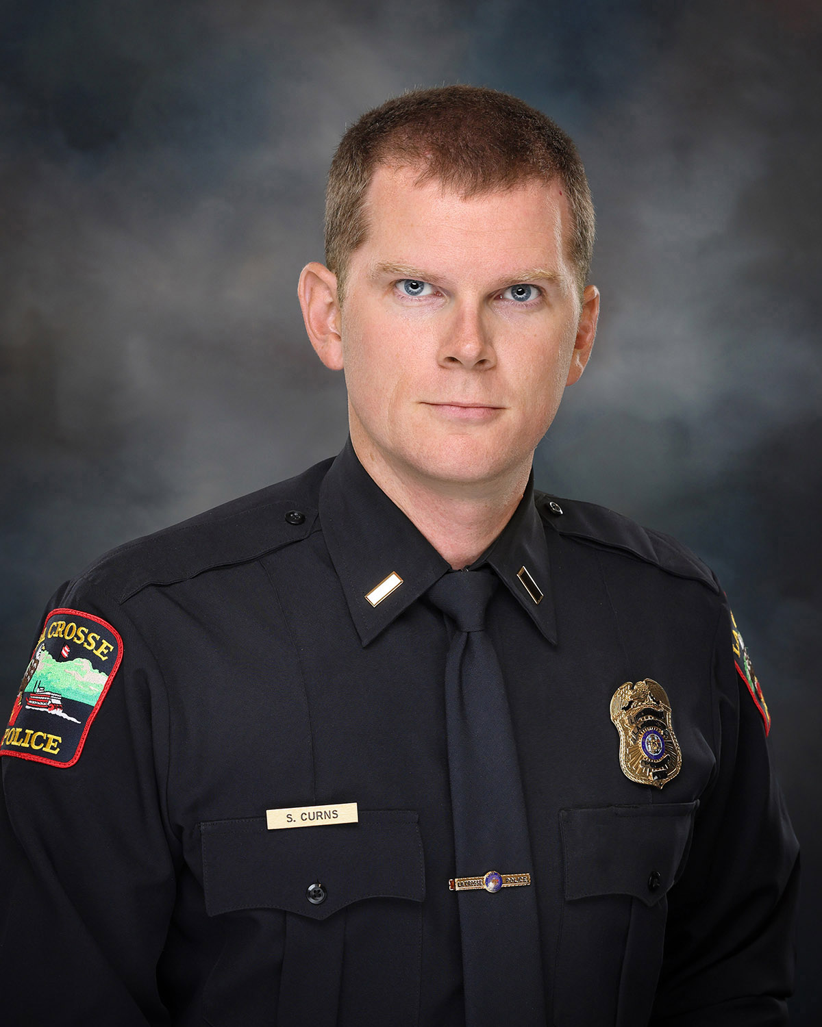 Professional portrait of a man in a police uniform.