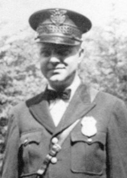A black and white photo of a man in a police uniform from 1936.